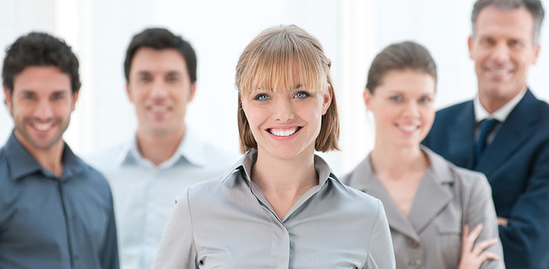 Happy smiling businesswoman standing with her colleagues at modern office